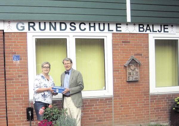 Foto: Dr. Henning Kehrberg überreicht Sylvia Einfeld von der Gundschule Balje eine der Boxen