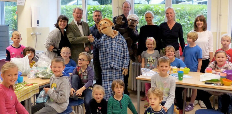 Foto: Gruppenfoto mit Schülern zwischen Kinderschutzbund, Puppenspielern, Lehrern und Klappfiguren.